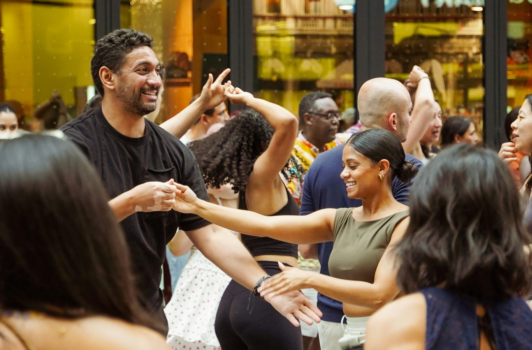 Smiling Salsa dancers welcoming each other on a busy floor